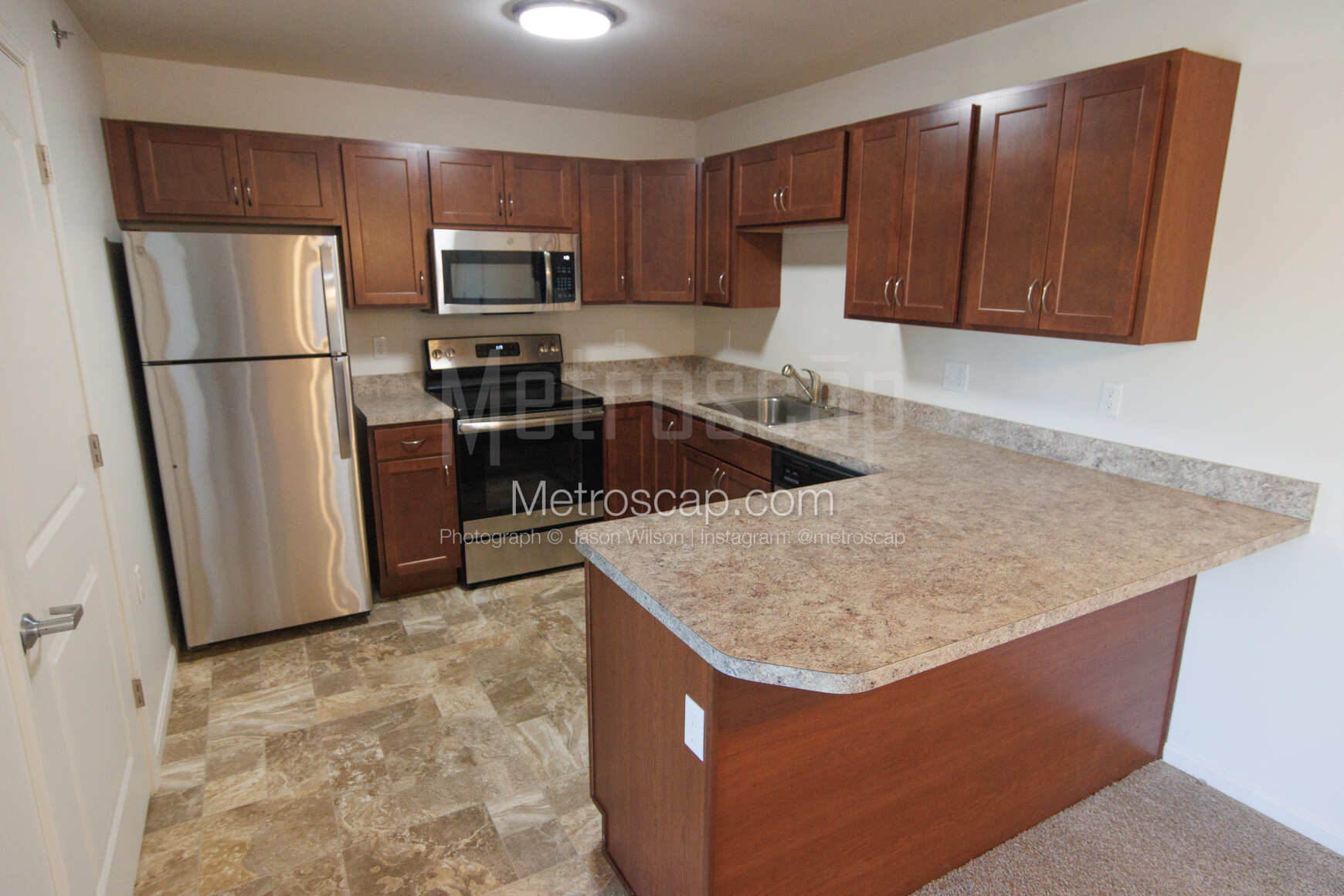 The interior of a clean kitchen with a refrigerator, stove, and microwave