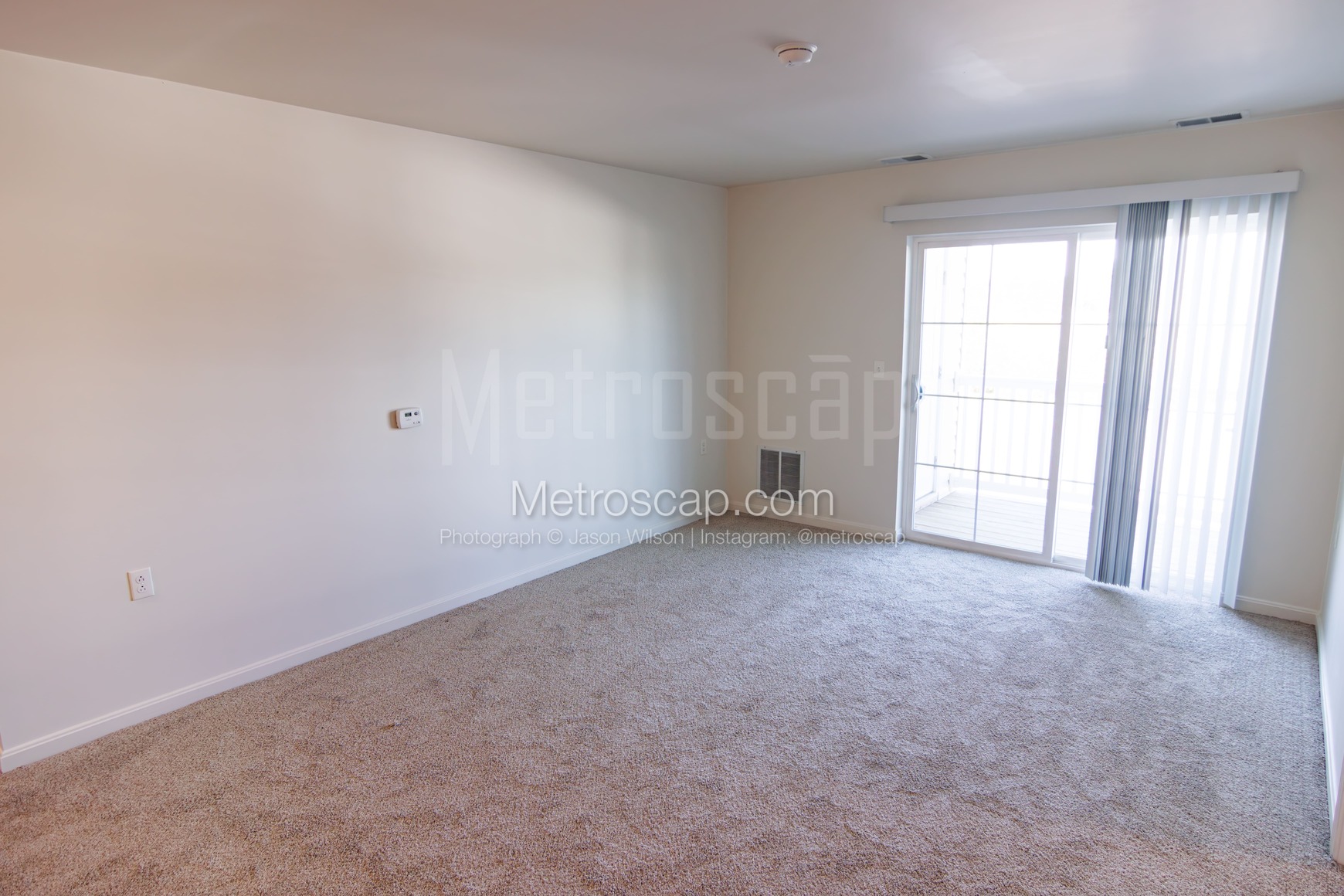 A living area with sliding glass doors featuring vertical blinds for privacy and light control.